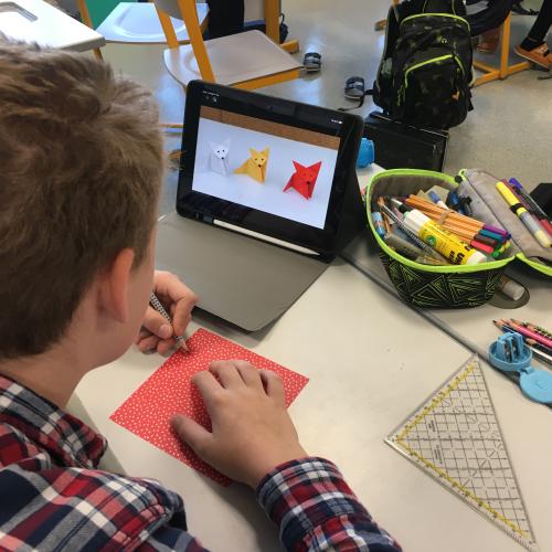Schüler sieht sich eine Anleitung für einen Origami-Fuchs am iPad an